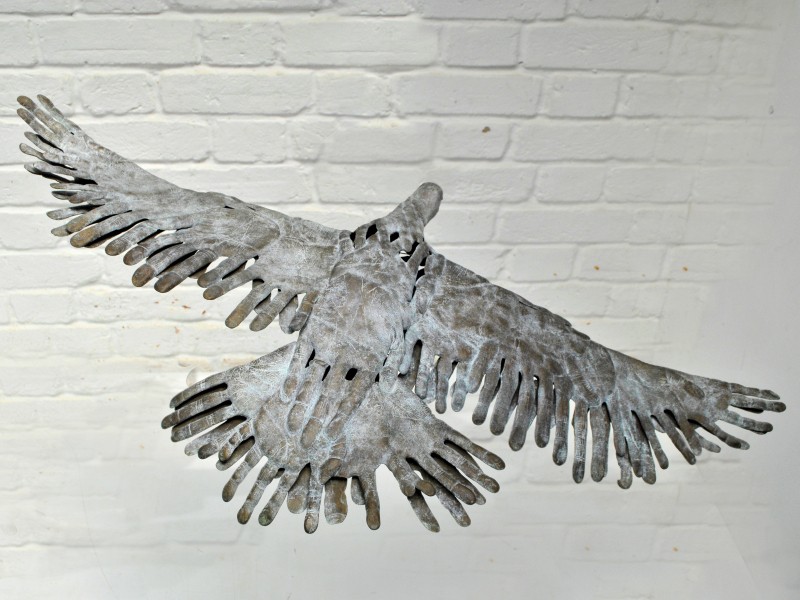 BIRD IN HAND - a bronze bird in flight made out of hand prints