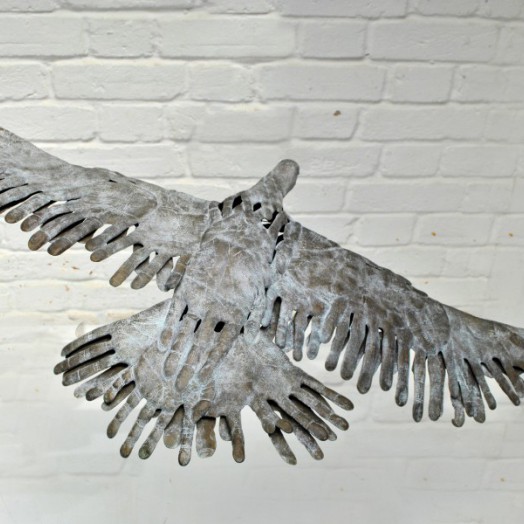 BIRD IN HAND - a bronze bird in flight made out of hand prints